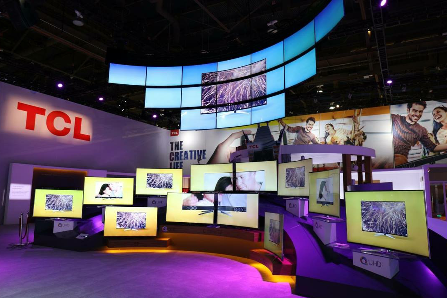 TCL booth display system with synchronized media playback across multiple monitors and overhead video walls.